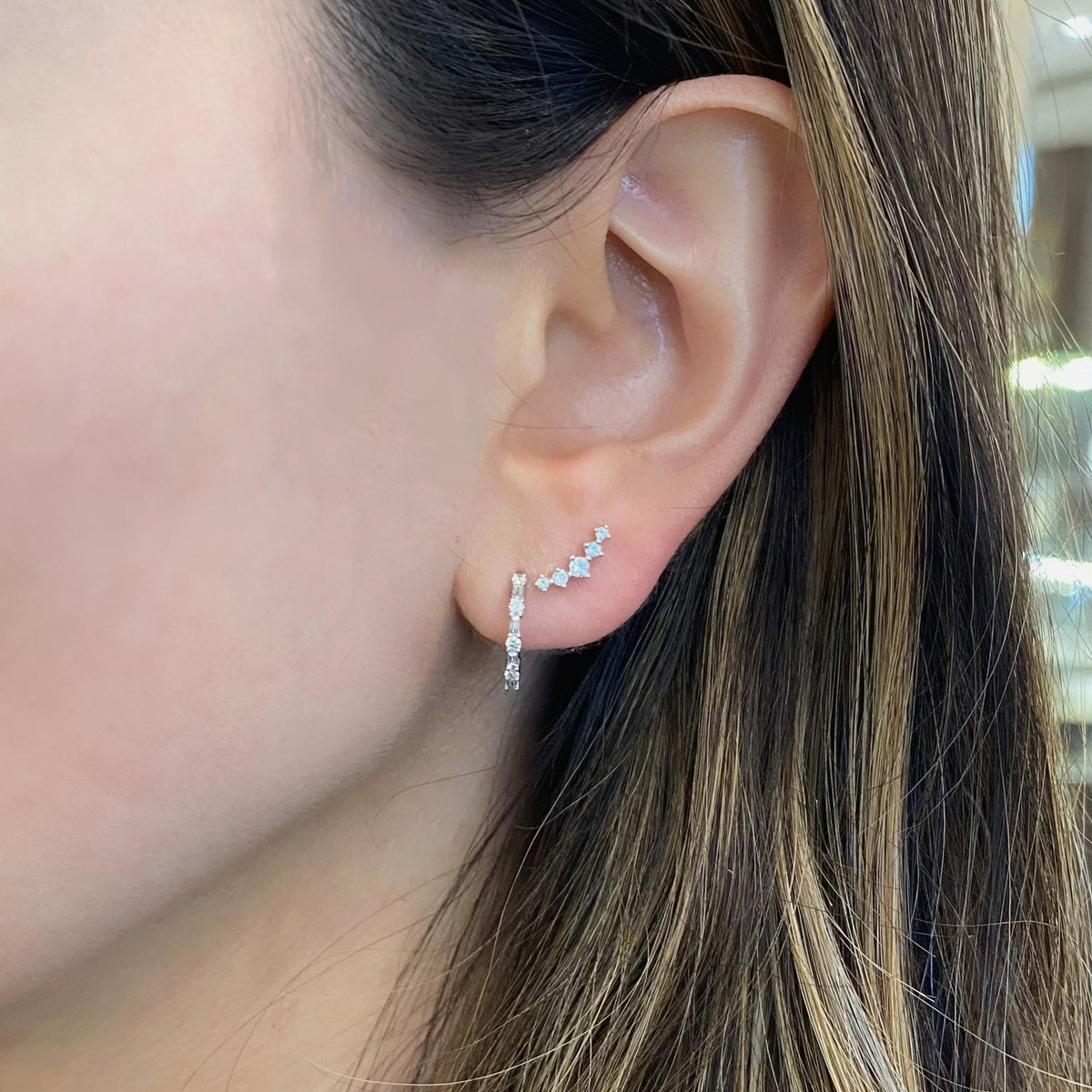 Female model wearing Round & Baguette Diamond Huggies - 14K gold weighing 1.43 grams  - 8 round diamonds weighing 0.13 carats  - 8 baguette diamonds weighing 0.12 carats