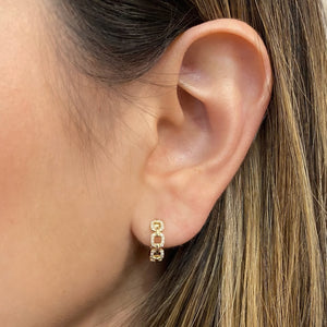 Female model wearing Diamond Chain Huggie Earrings - 14K yellow gold weighing 2.80 grams  - 52 round diamonds totaling 0.12 carats