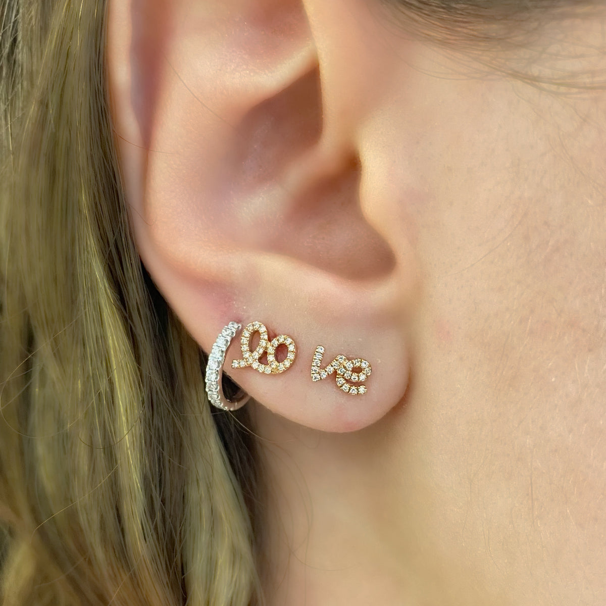 Female model wearing Diamond Love Script Stud Earrings - 14K gold weighing 1.16 grams - 48 round diamonds totaling 0.10 carats