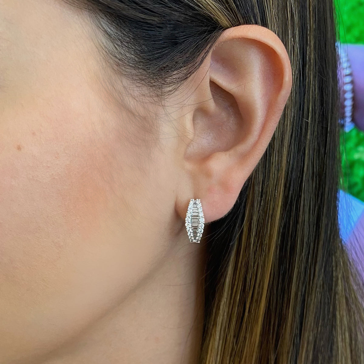 Female Model Wearing Baguette Diamond Huggie Earrings   -14K gold weighing 4.95 grams   -40 round diamonds totaling 0.56 carats   -27 straight baguettes totaling 0.38 carats