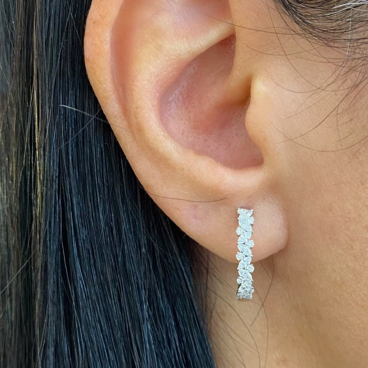 Female model wearing Huggies With Round & Marquise Diamonds -18K white gold weighing 3.63 grams -16 marquise diamonds weighing 0.45 carats -18 round diamonds weighing 0.17 carats