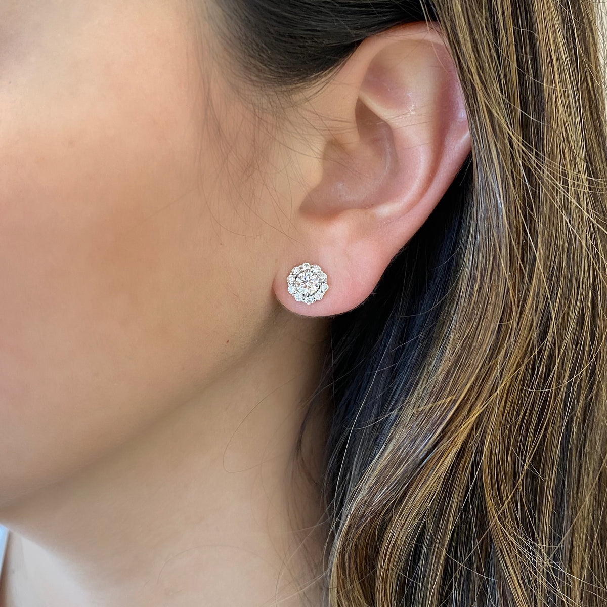 female model wearing diamond halo stud earrings - 18K gold weighing 2.95 grams - 20 round diamonds totaling 0.51 carats - 2 round diamonds totaling 0.78 carats