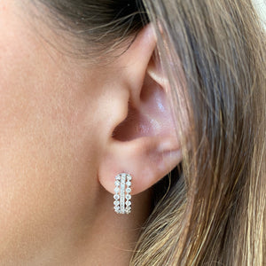 Female model wearing Diamond Triple Row Huggie Earrings - 18K gold weighing 3.63 grams - 52 round diamonds weighing 0.93 carats
