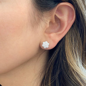 Female model wearing Diamond Flower Stud Earrings - 18K white gold weighing 2.23 grams - 74 round diamonds weighing 0.91 carats