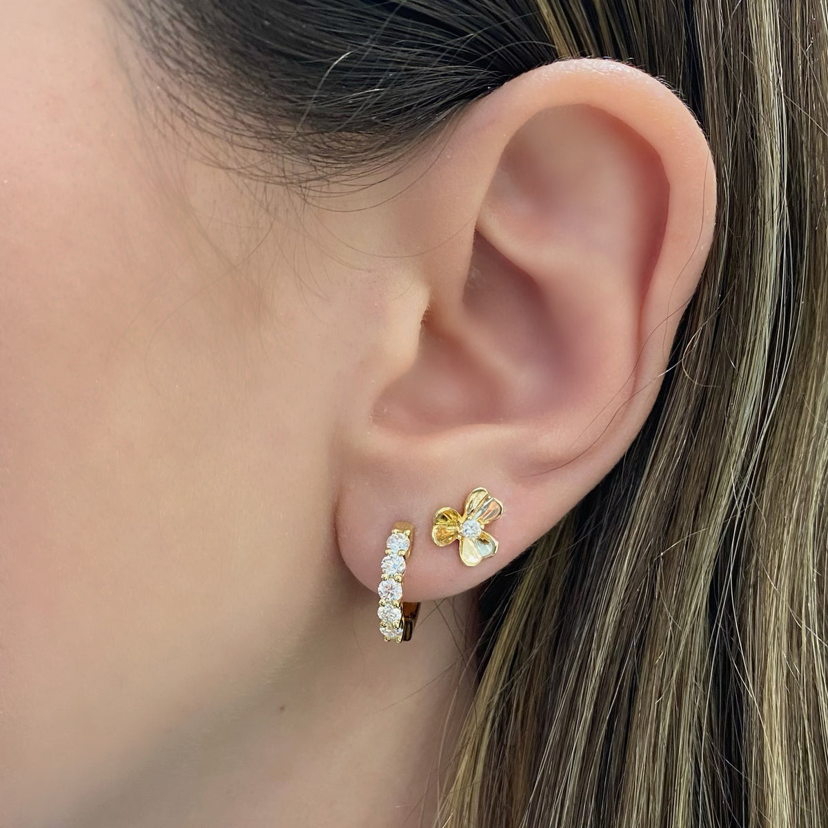 Female model wearing Diamond Accent Clover Stud Earrings - 14K yellow gold weighing 2.47 grams - 2 round diamonds totaling 0.10 carats