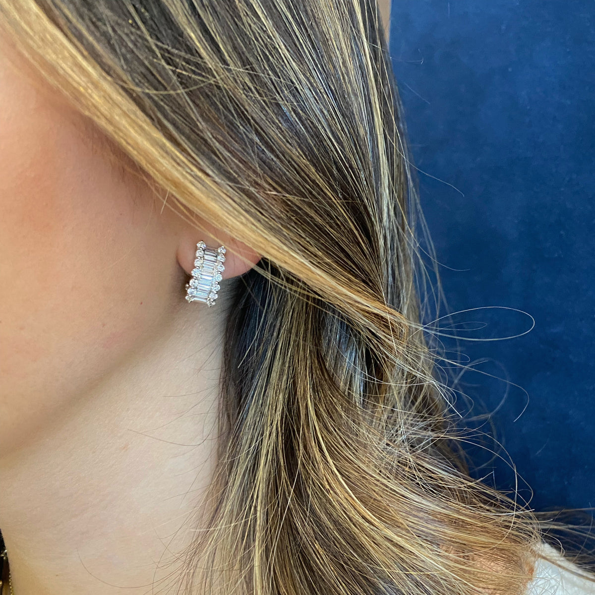 Female model wearing Baguette & Round Diamond Half Hoop Earrings - 18K white gold weighing 6.87 grams - 28 round diamonds weighing 0.96 carats - 20 baguette diamonds weighing 1.04 carats