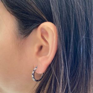 Female model wearing Sapphire & diamond huggie earrings - 18K gold weighing 4.31 grams  - 10 sapphires totaling 0.66 carats  - 8 round diamonds totaling 0.40 carats