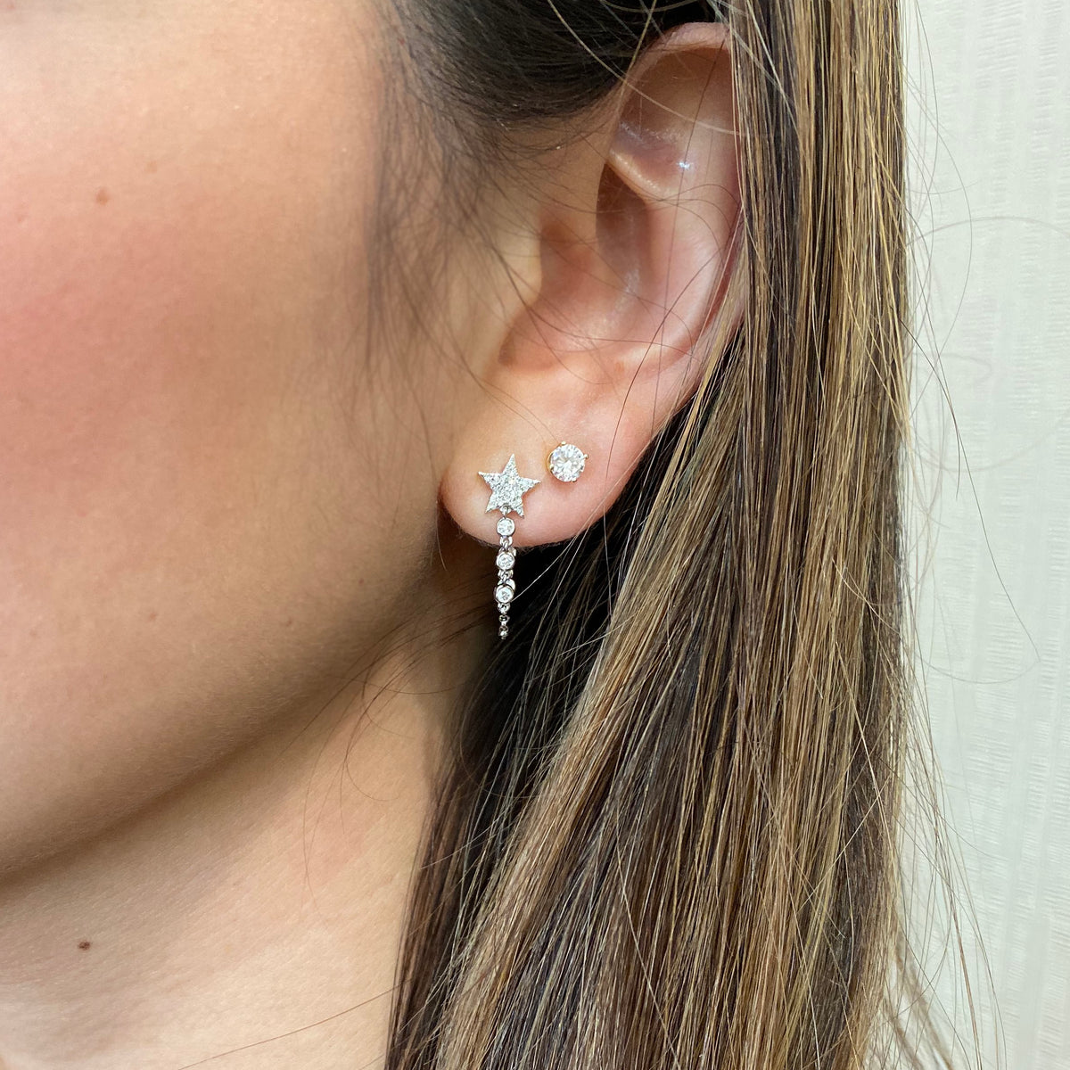 Female model wearing Diamond Star Chain Link Earrings - 14K gold weighing 1.89 grams - 10 round diamonds totaling 0.16 carats - 52 pave diamonds totaling 0.11 carats