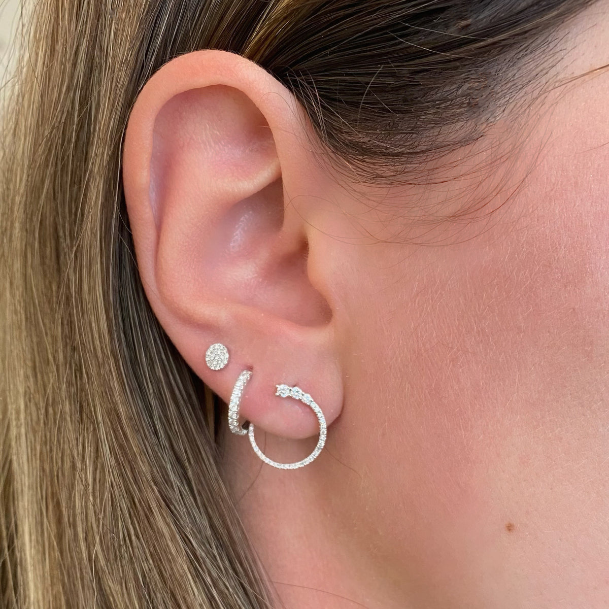 Female Model Wearing Diamond Push-Back Hoop Earrings -14k gold weighing 1.77 grams  -20 round diamonds weighing .32 carats