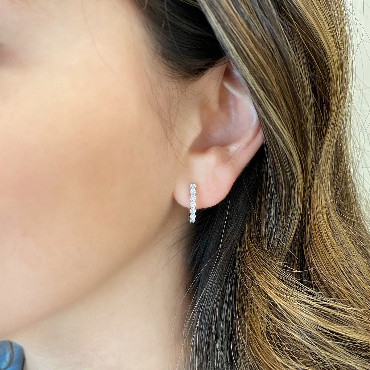 Female model wearing Round diamond huggie earrings - 14 round diamonds totaling 0.53 carats  - 18K gold weighing 1.75 grams