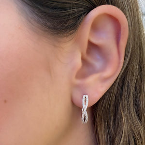 Female model wearing Diamond twist hoop earrings - 18K gold weighing 5.42 grams  - 64 round diamonds totaling 0.53 carats