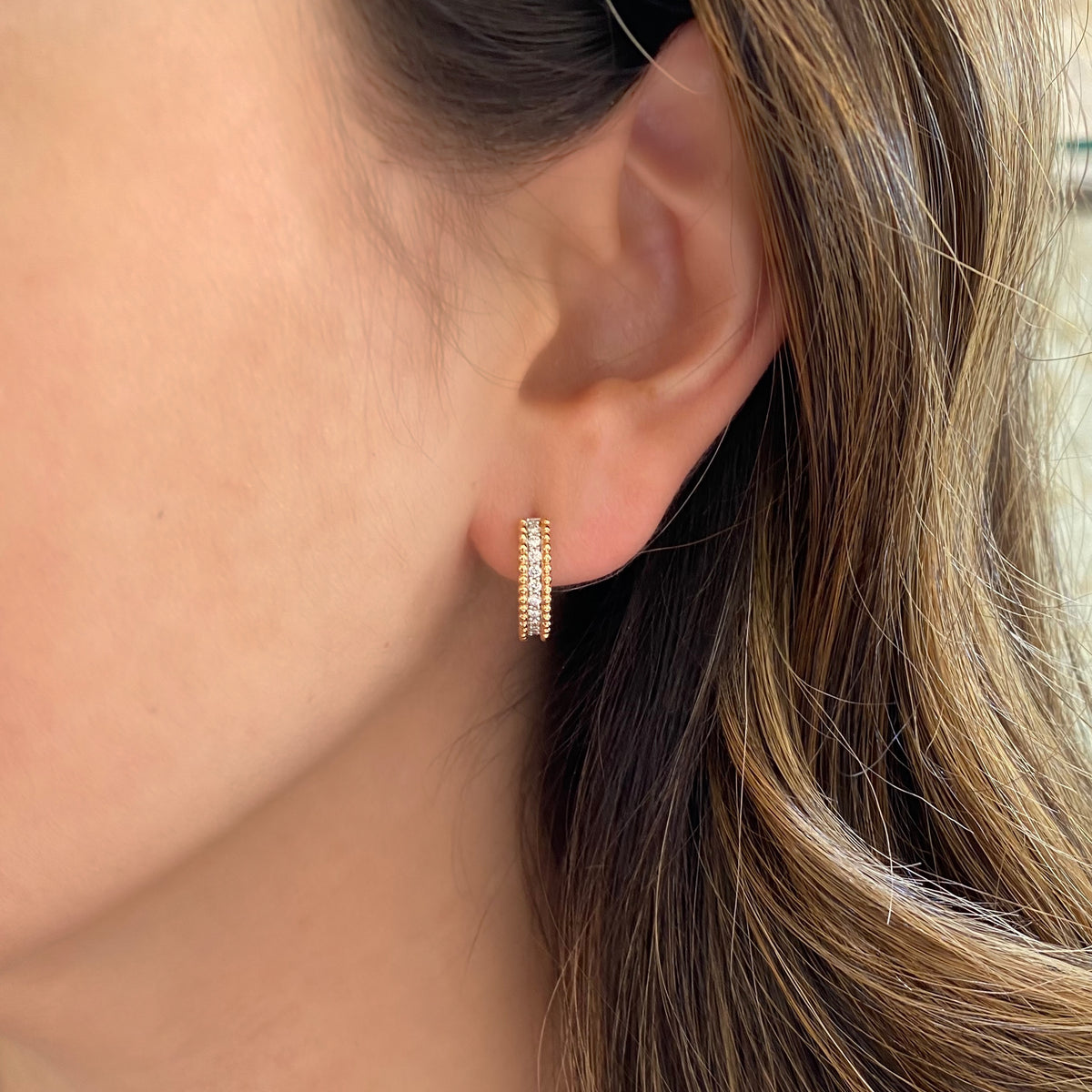 Female model wearing Diamond & Beaded Three-Row Gold Huggie Earrings - 18K gold weighing 3.90 grams - 20 round diamonds totaling 0.23 carats