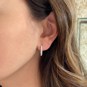 Female model wearing Diamond huggie earrings - 18K gold weighing 2.72 grams  - 18 round diamond totaling 0.66