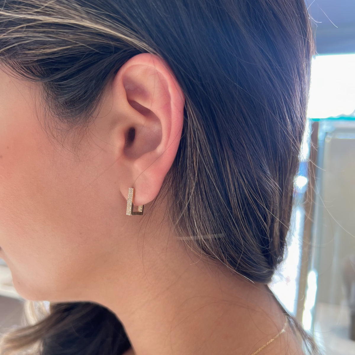 Female Model Wearing Diamond Square Huggie Earrings - 14K gold weighing 2.63 grams  - 78 round diamonds totaling 0.18 carats