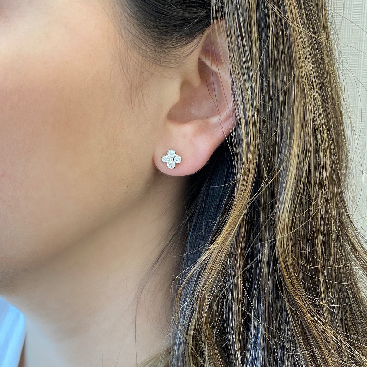 Female model wearing Clover Diamond Stud Earrings -Platinum weighing 2.6 grams -8 round bezel-set diamonds weighing .45 carats