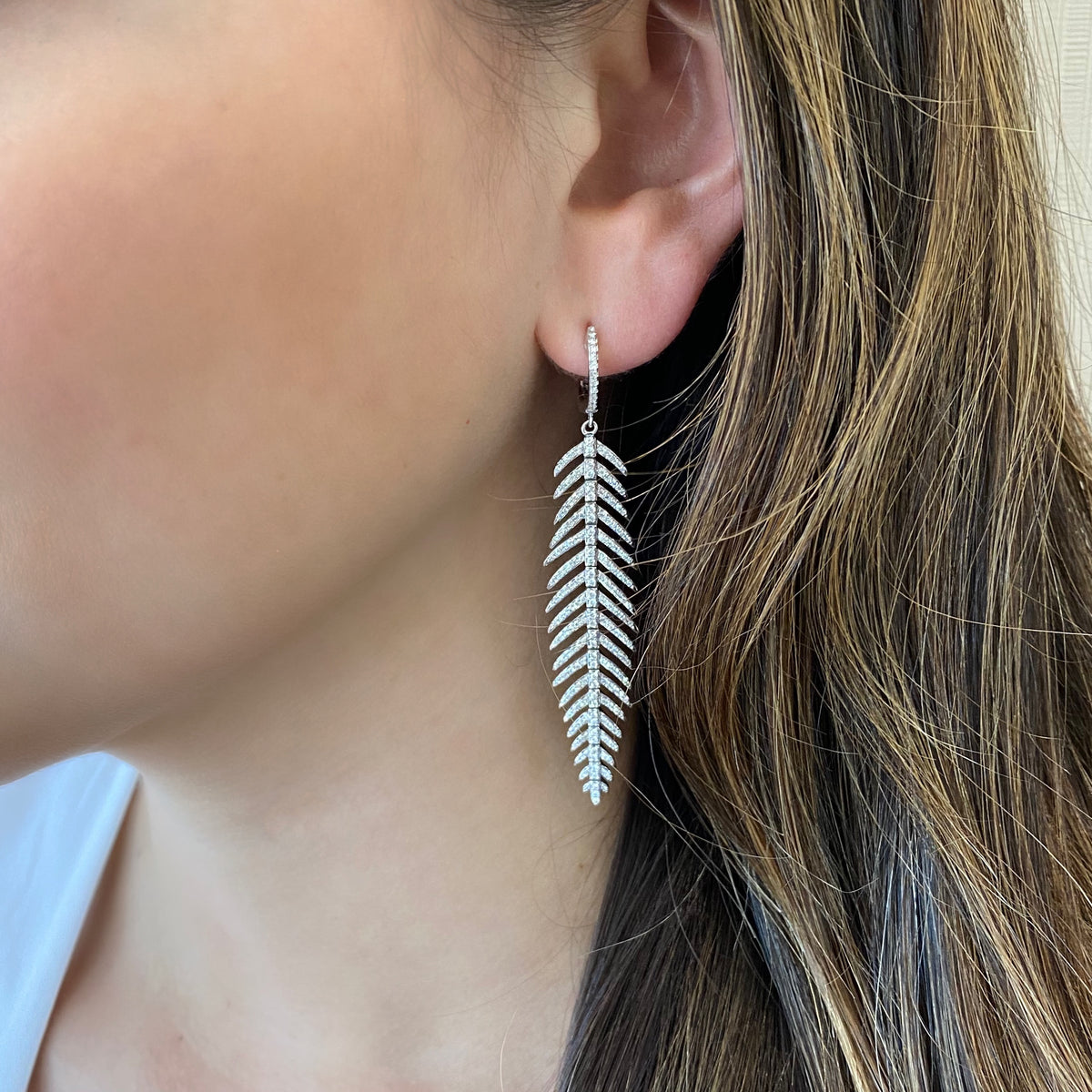 Female Model Wearing Diamond Feather Dangle Earrings  - 14K gold weighing 10.73 grams  - 436 round diamonds totaling 1.29 carats