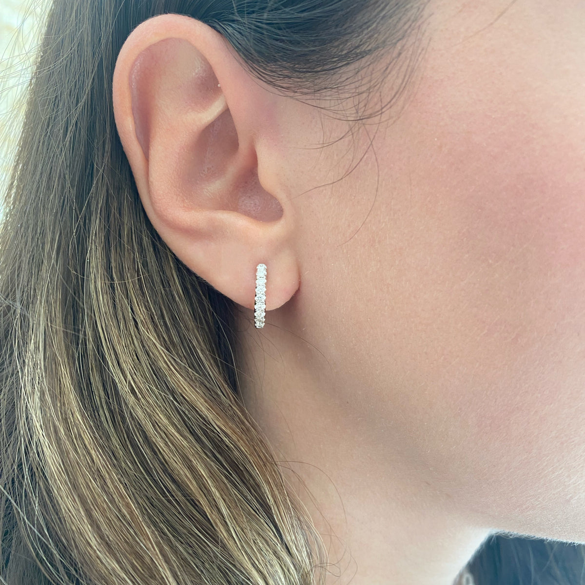 Female Model Wearing Solid 14K yellow gold weighing 2.77 grams featuring 18 round diamonds weighing 0.39 carats 0.39 ct Huggie Earrings | Nuha Jewelers