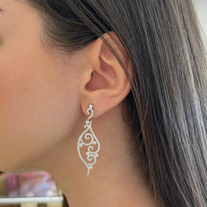Female model wearing Diamond Swirl Earrings 18k gold, 6.88 grams, 14 round prong-set diamonds .8 carats, 200 round shared prong-set diamonds 2.22 carats.