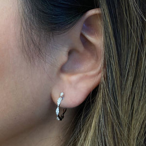 Female Model Wearing Large Diamond Wavy Hoop Earrings -18K gold weighing 2.72 grams  -20 round diamonds totaling 0.21 carats