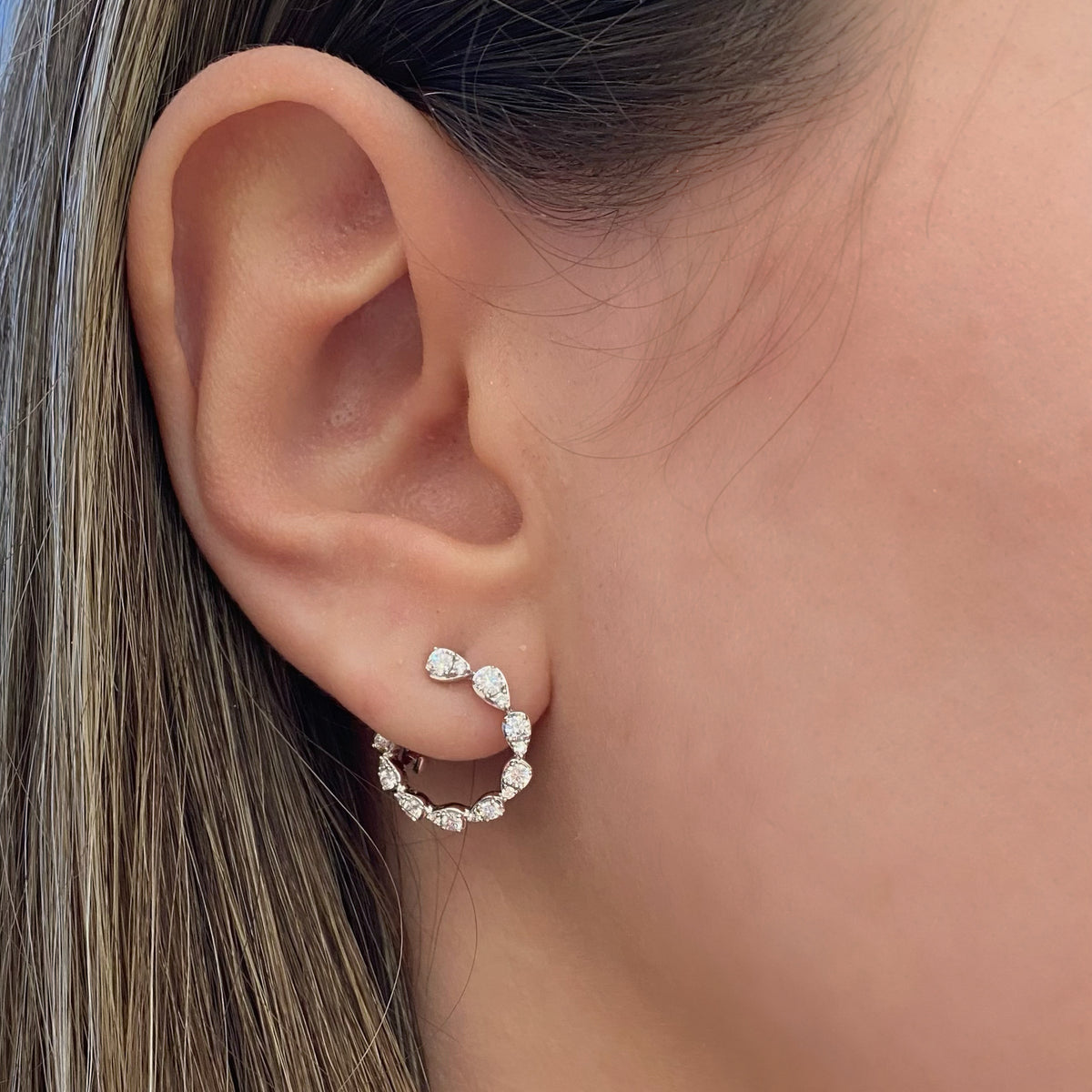 Female model wearing Diamond teardrops front-facing hoop earrings - 14K yellow gold weighing 3.76 grams  - 8 round diamonds totaling 0.38 carats  - 28 round diamonds totaling 0.36 carats