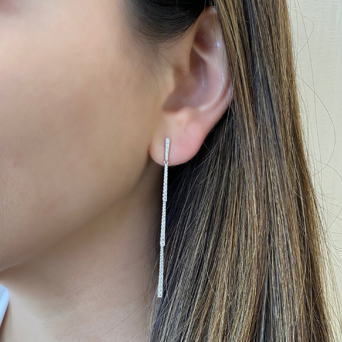 Female model wearing Diamond Classic Linear Dangle Earrings -18K gold weighing 3.99 grams -90 round diamonds totaling 0.76 carats