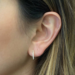 Female Model Wearing Oval Diamond Huggie Earrings -18k gold weighing 1.64 grams  -18 round diamonds weighing .20 carats