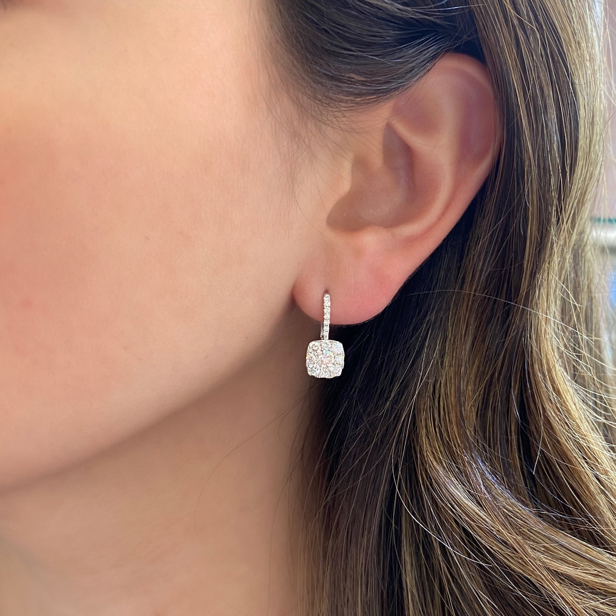 Female Model Wearing Diamond Square Cluster Lever-Back Earrings  -18K gold weighing 2.79 grams  -30 round shared prong-set diamonds totaling 0.93 carats  -2 round diamonds totaling 0.52 carats.