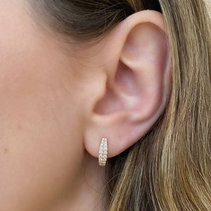 Female model wearing Graduated diamond double row huggie earrings - 14K gold weighing 2.37 grams  - 44 round diamonds totaling 0.39 carats