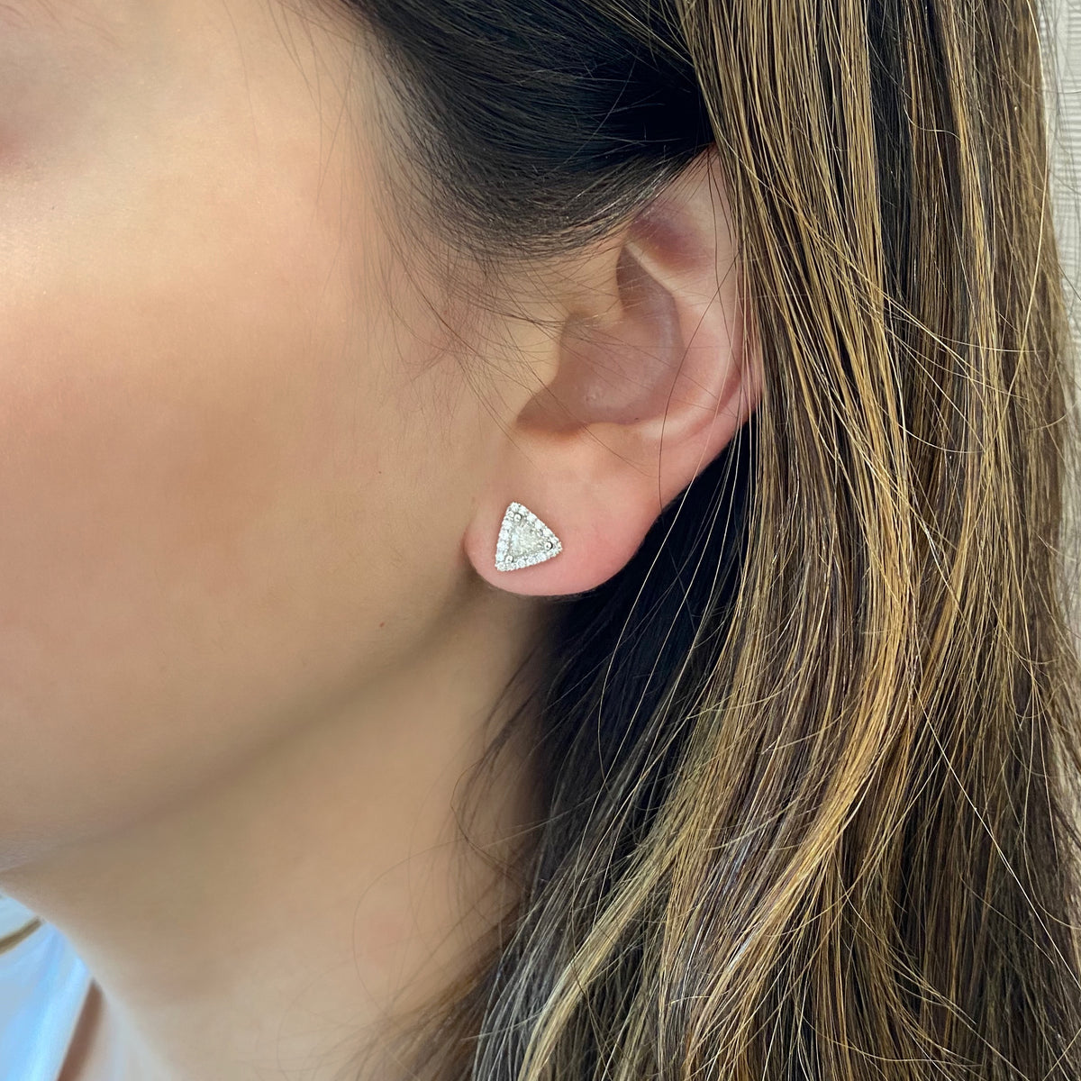 female model wearing triangle-shaped diamond earrings 18k gold, 2.61 grams, 36 round shared prong-set diamonds .20 carats, 2 triangle prong-set brilliant diamonds .59 carats.