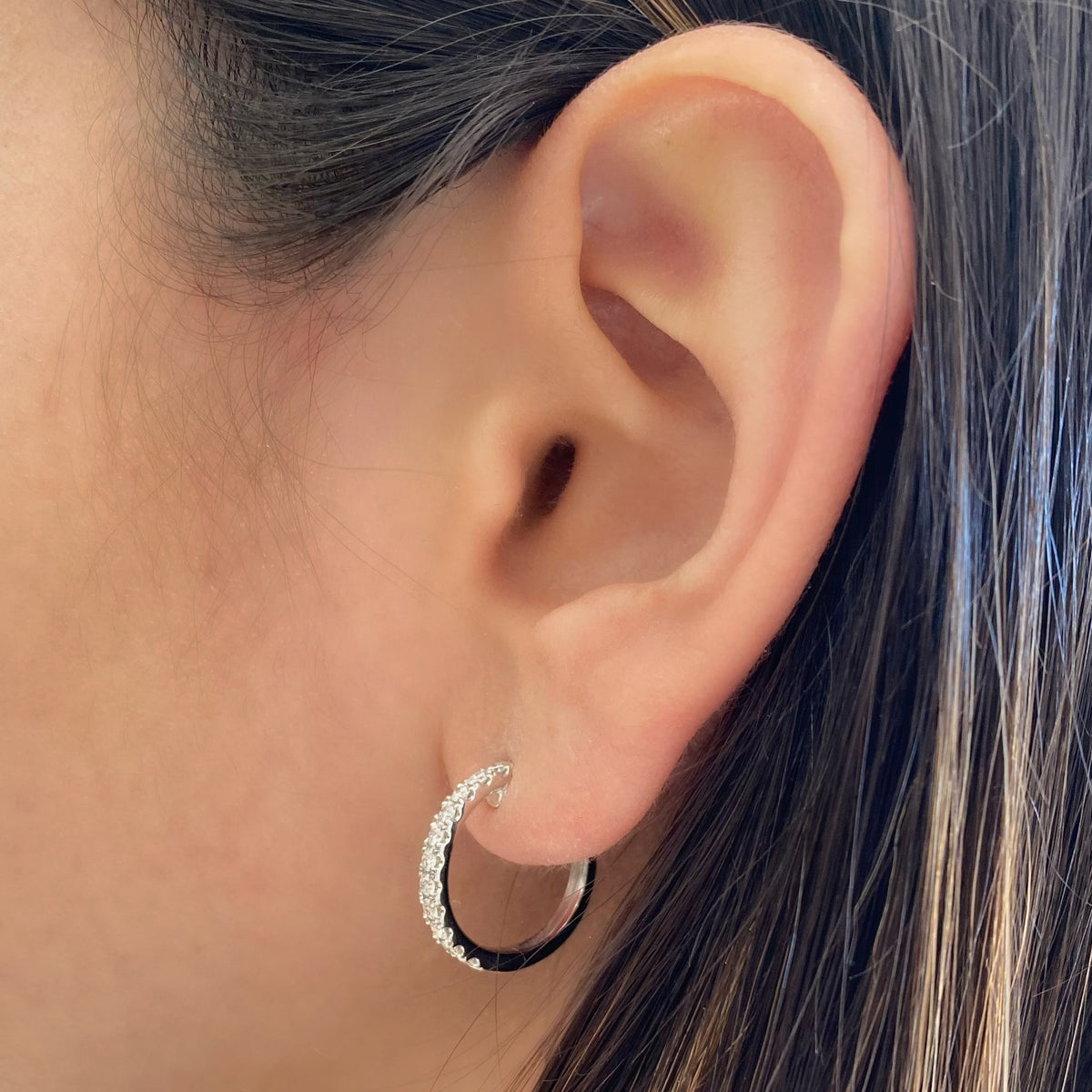 Female model wearing Classic diamond huggie earrings - 18K gold weighing 3.83 grams  - 22 round diamonds totaling 0.47 carats