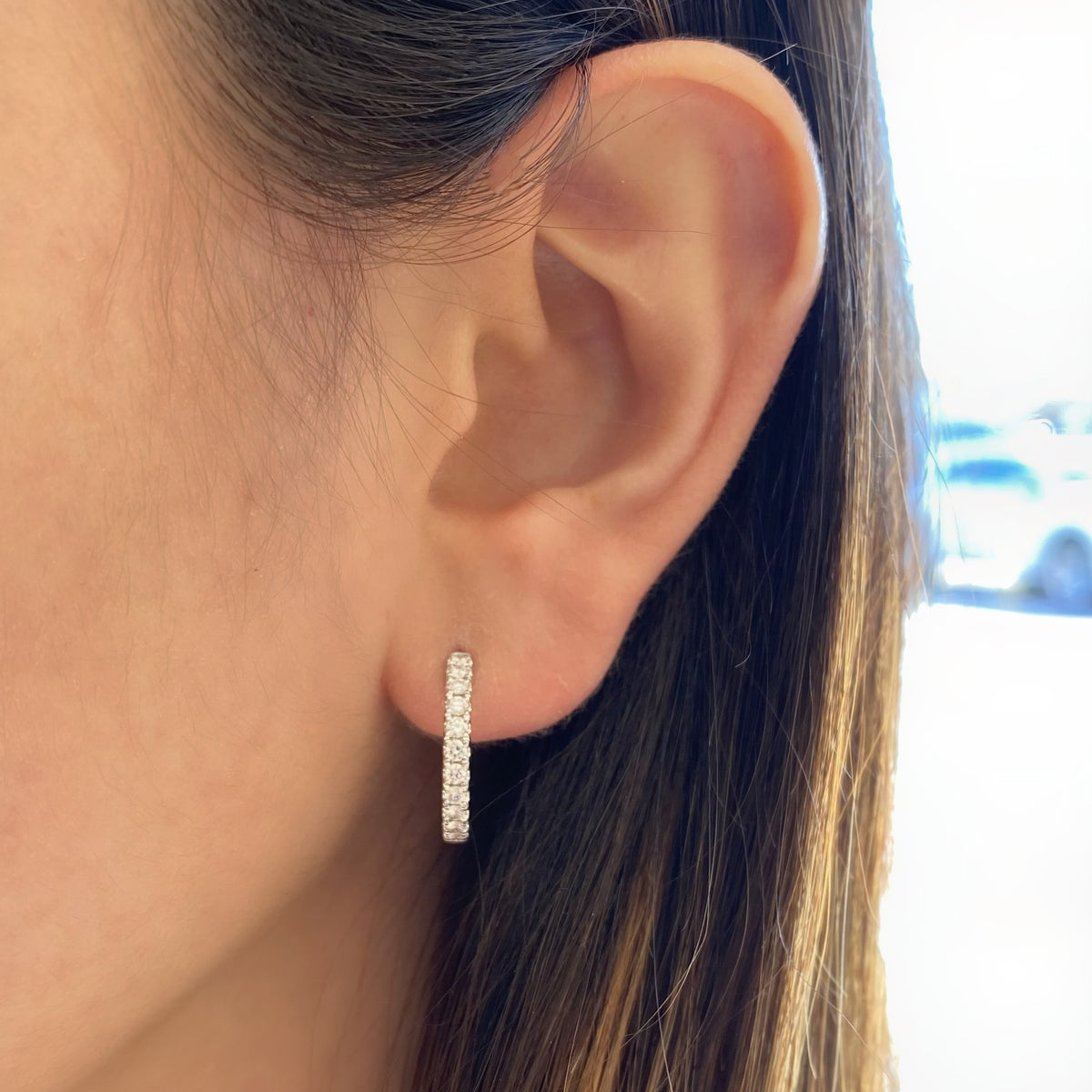 Female model wearing Classic diamond huggie earrings - 18K gold weighing 3.83 grams  - 22 round diamonds totaling 0.47 carats