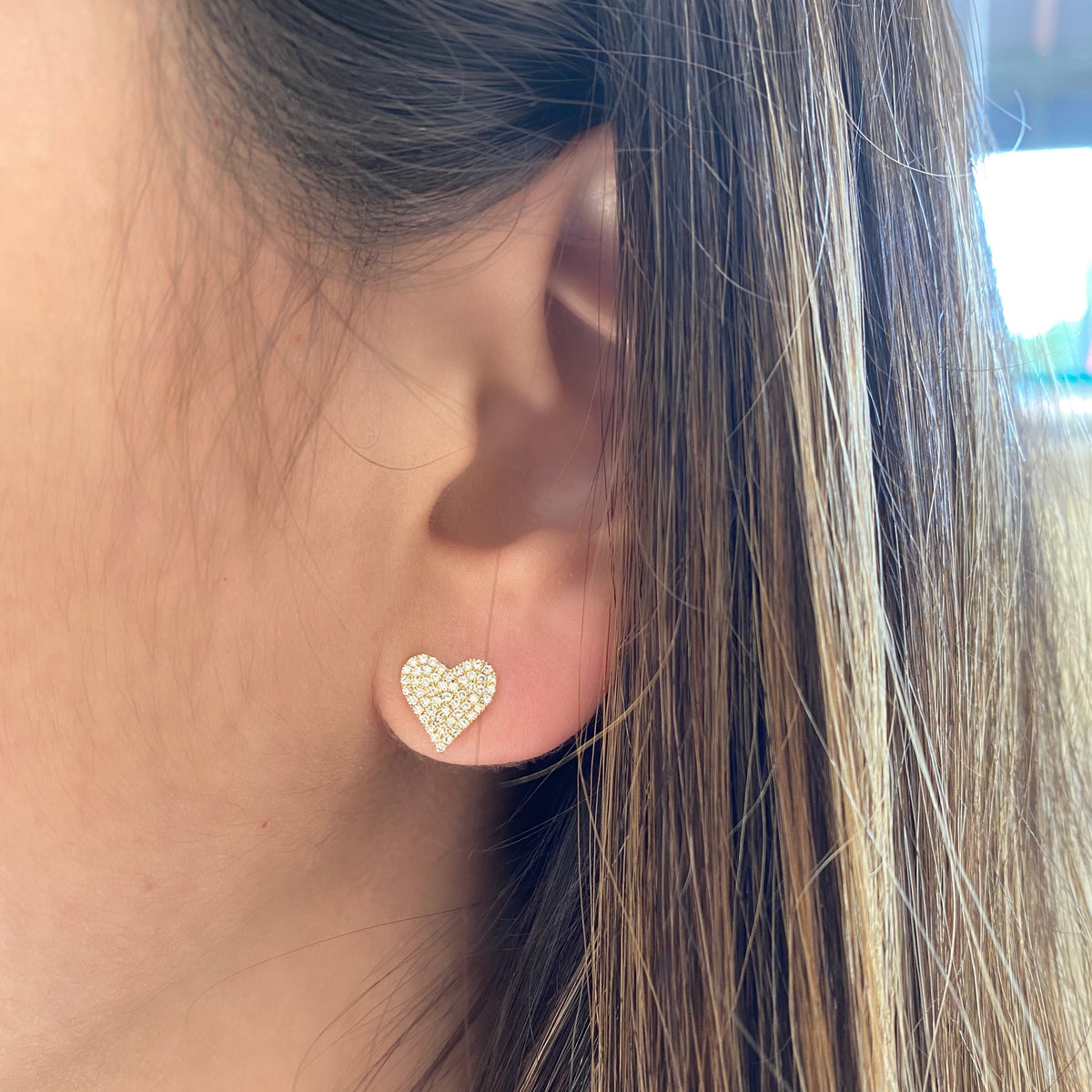 Female model wearing Diamond Heart Earrings -14k yellow gold weighing 1.56 grams - 106 round pave-set diamonds totaling 0.33 carats.