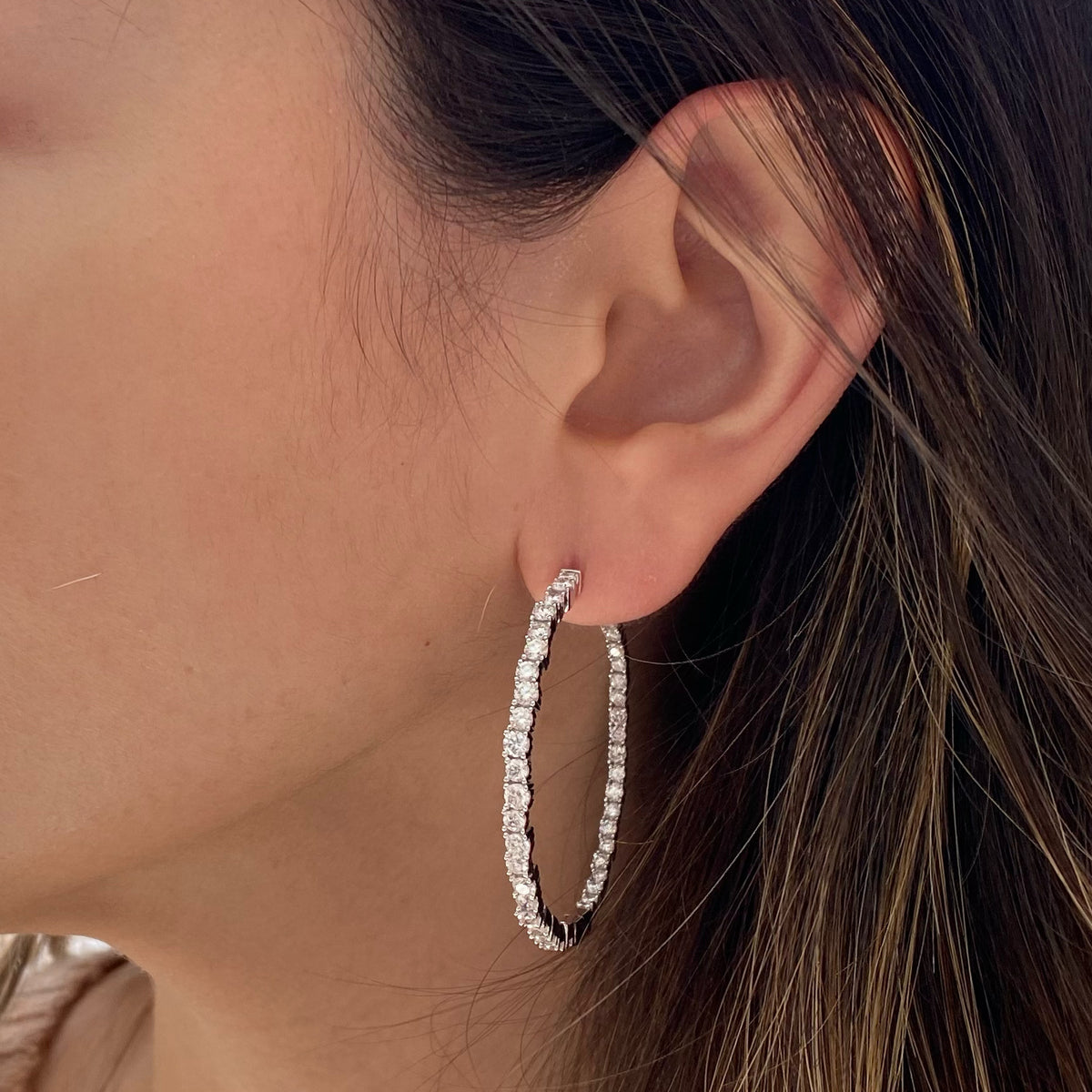 Female model wearing Large diamond scattered hoop earrings -14k gold weighing 13.65 grams -88 round prong-set diamonds weighing 4.35 carats