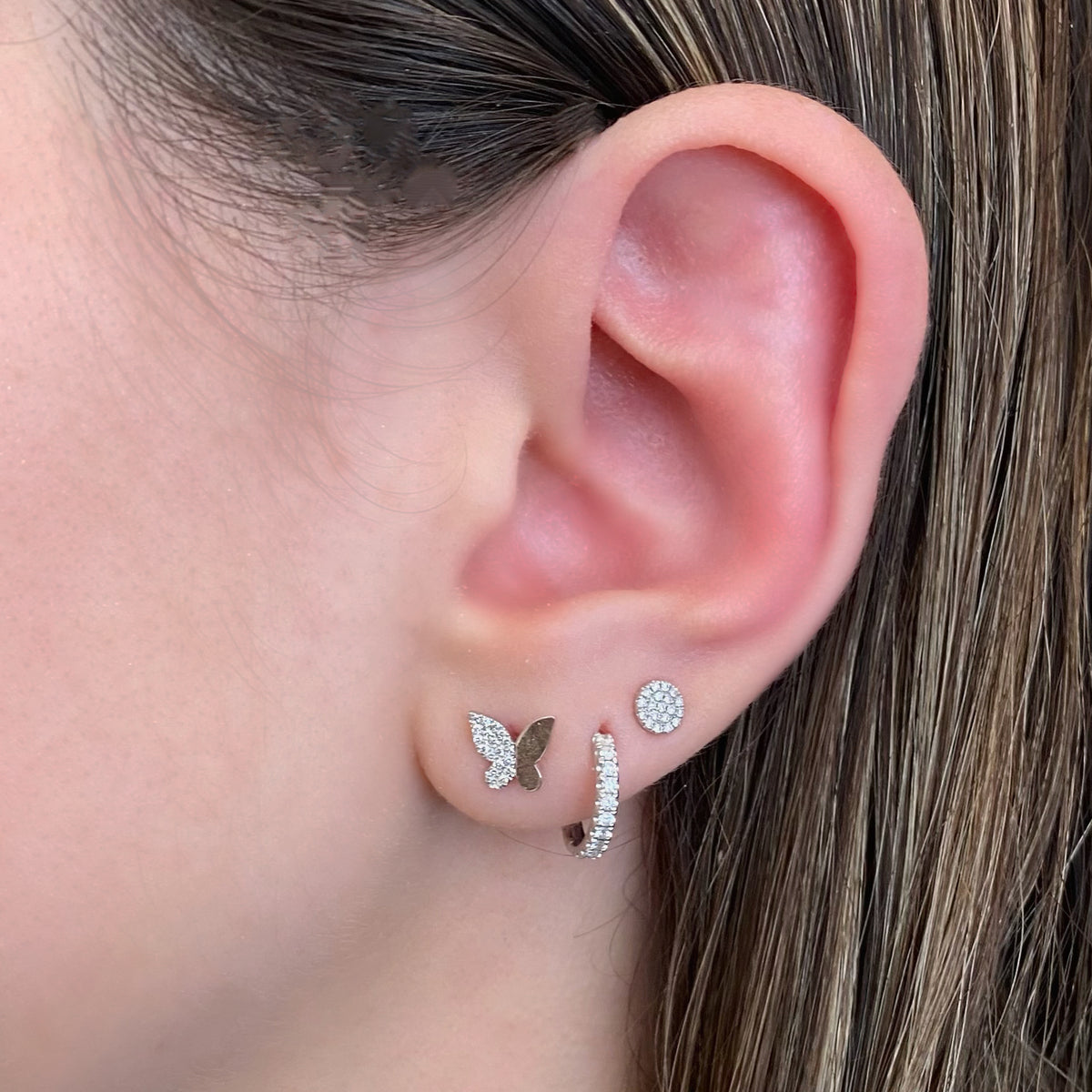 Female model wearing Half Diamond Butterfly Stud Earrings - 14K gold weighing 1.30 grams - 38 round diamonds totaling 0.09 carats