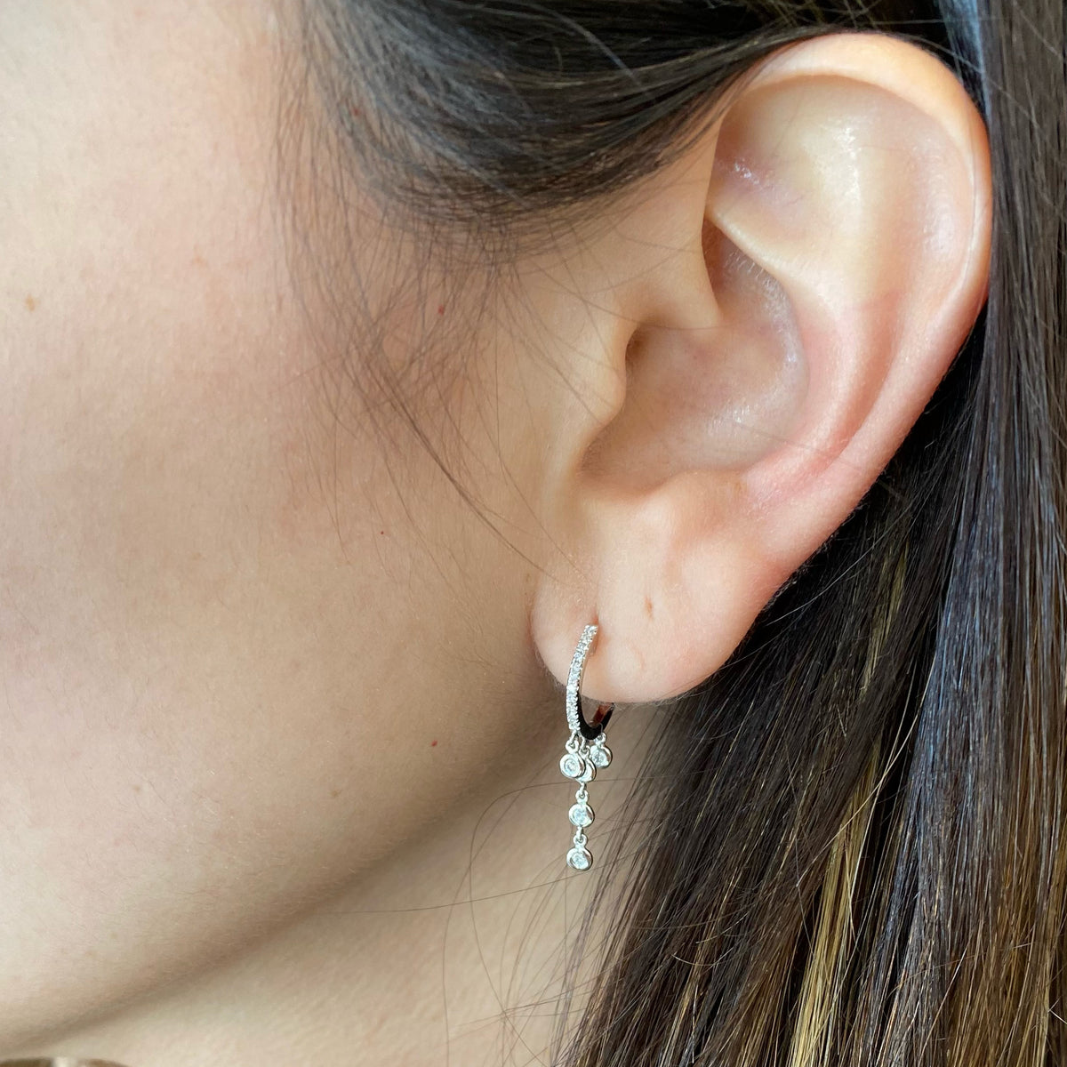 Female Model Wearing Gold Huggie Earring With Diamond 5-Bezel Drop Earrings -14k gold weighing 1.91 grams  -32 round diamonds weighing .15 carats