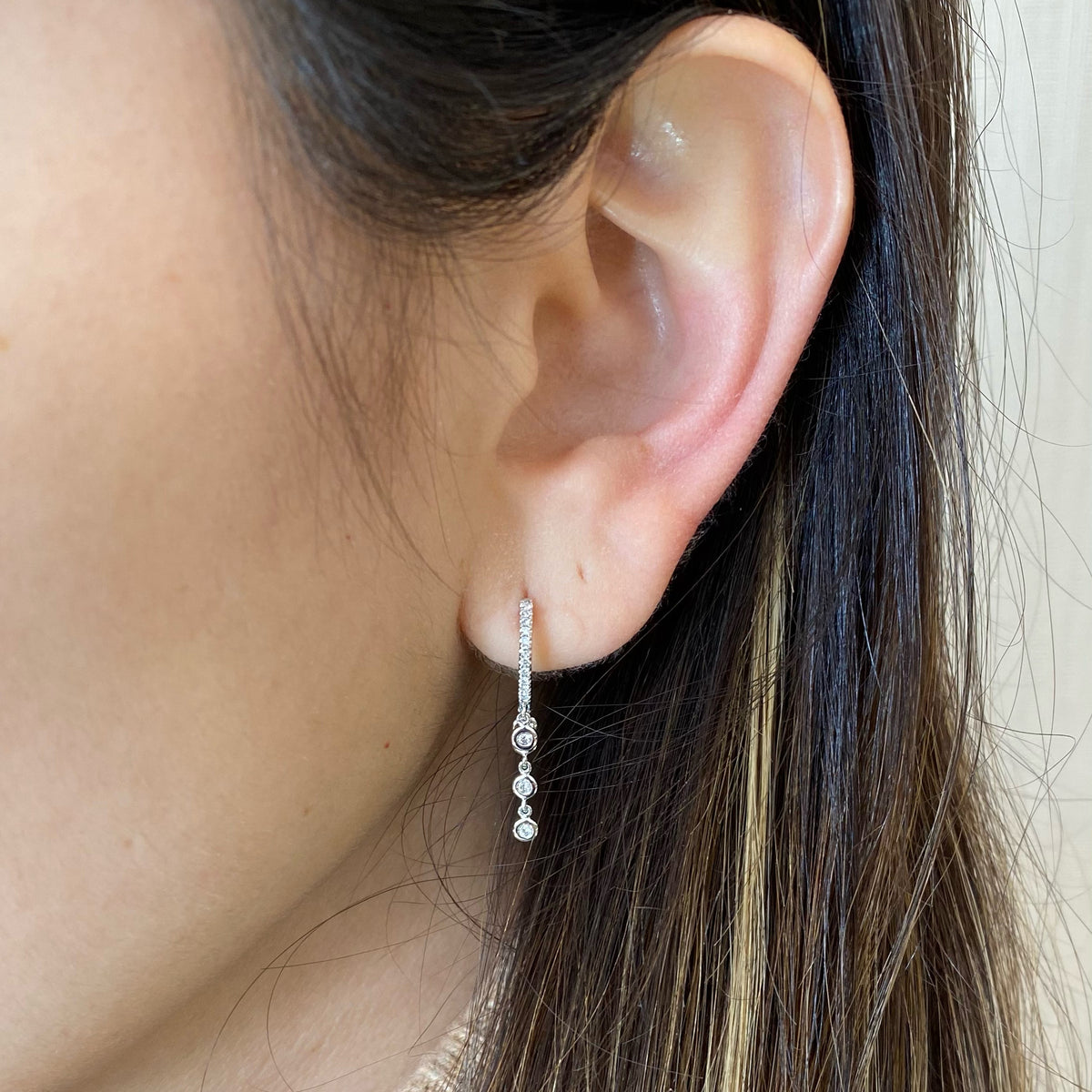 Female Model Wearing Gold Huggie Earring With Diamond 5-Bezel Drop Earrings -14k gold weighing 1.91 grams  -32 round diamonds weighing .15 carats