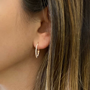 Female model wearing Diamond interior & exterior huggie earrings - 14K gold weighing 2.09 grams  - 38 round diamonds totaling 0.38 carats