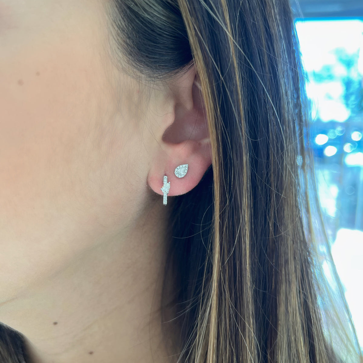 Female model wearing Round & Pear-Shaped Diamond Huggies -18K gold weighing 1.64 grams  -14 round diamonds weighing 0.10 carats  -2 pear-shaped diamonds weighing 0.29 carats