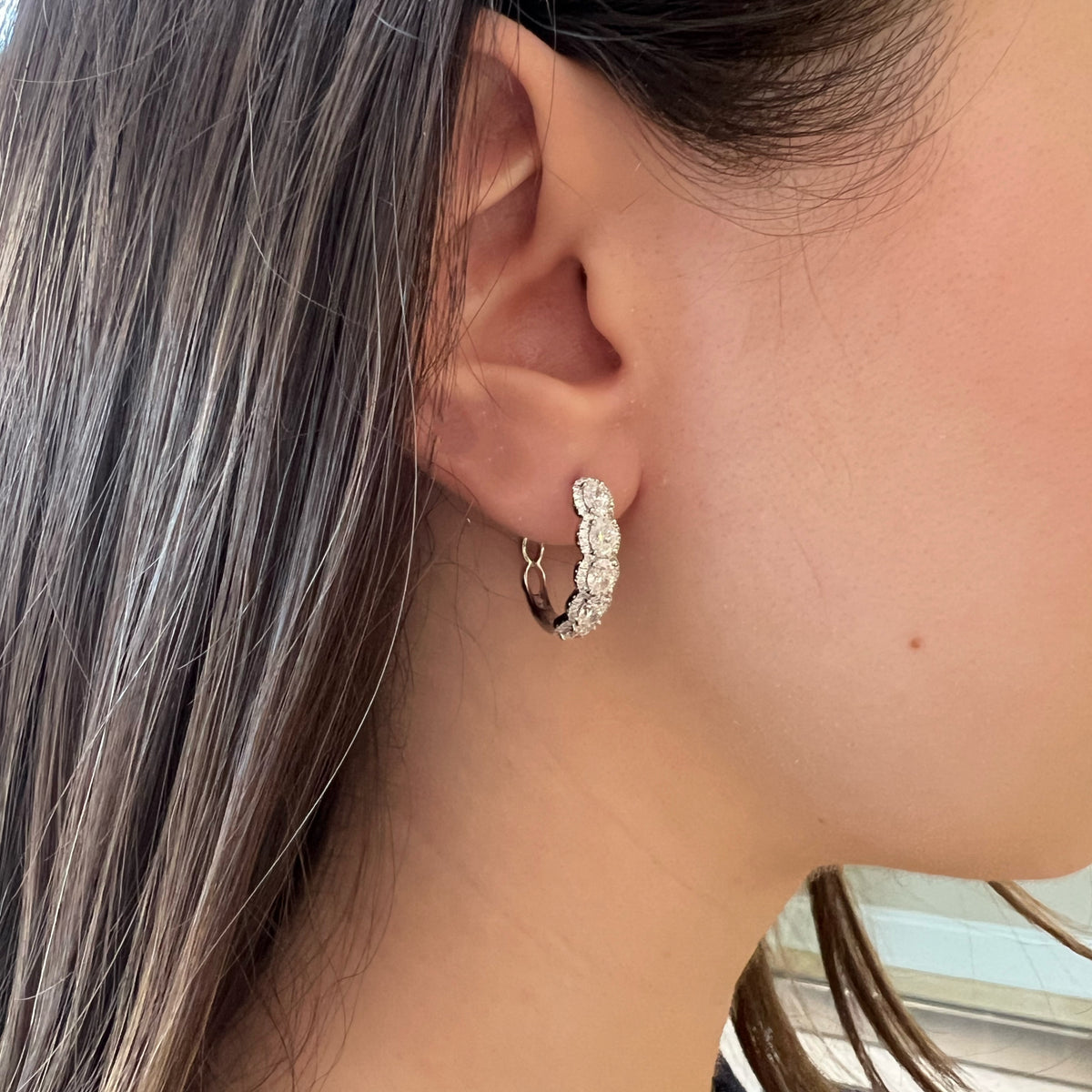 Female model wearing Diamond Oval Hoop Earrings - 18K gold weighing 5.68 grams  - 10 oval-shaped diamonds weighing 2.16 carats  - 112 round diamonds weighing 0.39 carats