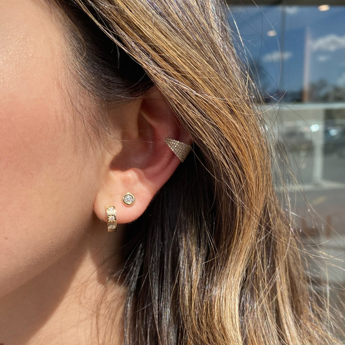 Female Model Wearing Diamond Star Huggie Earrings - 14K gold weighing 2.98 grams  - 6 round diamonds weighing 0.10 carats