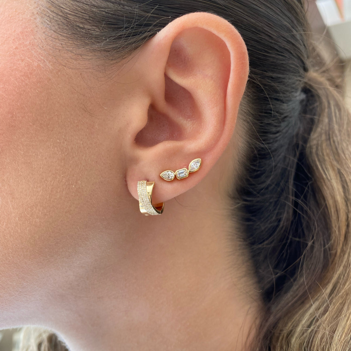 Female Model Wearing Diamond and Gold Crossover Huggie Earrings - 14K gold weighing 3.98 grams  - 156 round diamonds weighing 0.31 carats