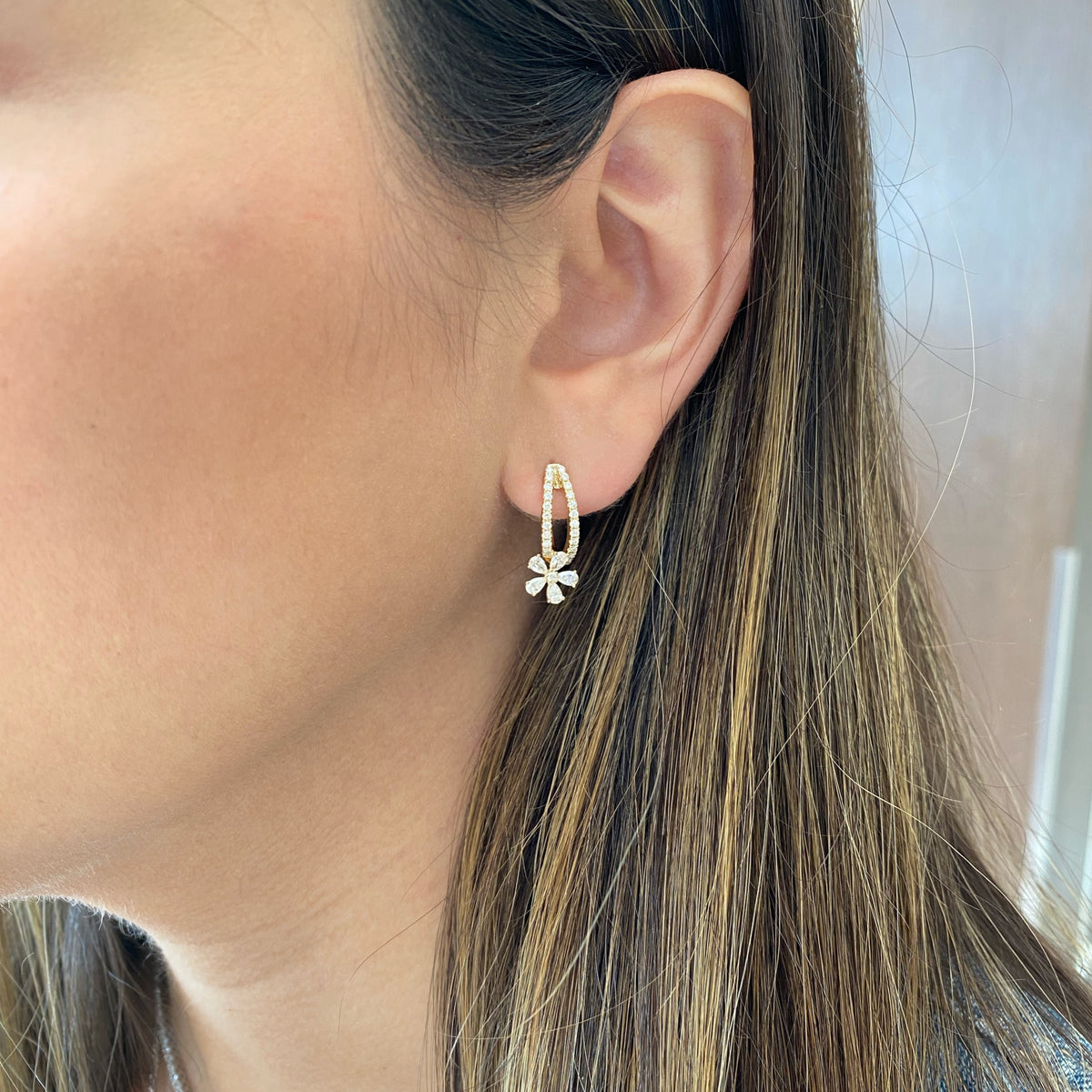 Female Model Wearing Diamond Flower Drop Huggie Earrings - 14K gold weighing 3.37 grams  - 46 round diamonds weighing 0.33 carats  - 10 pear-shaped diamonds weighing 0.55 carats