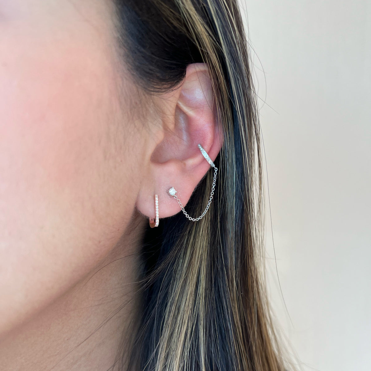 Female model wearing Diamond Square Huggie Earrings - 14K yellow gold weighing 1.19 grams  - 24 round diamonds totaling 0.07 carats