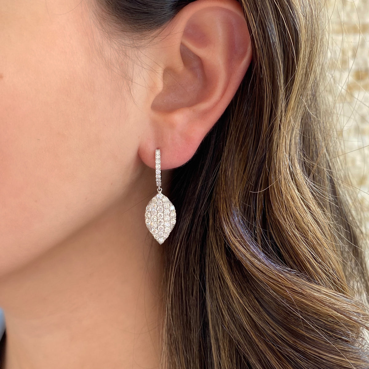 Female model wearing Diamond Simple Dangle Earrings -18K gold weighing 5.27 grams -74 round diamonds totaling 2.75 carats