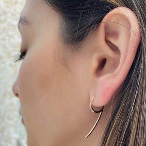 Female model wearing Diamond '9' huggie earrings - 14K gold  - 0.18 cts round diamonds