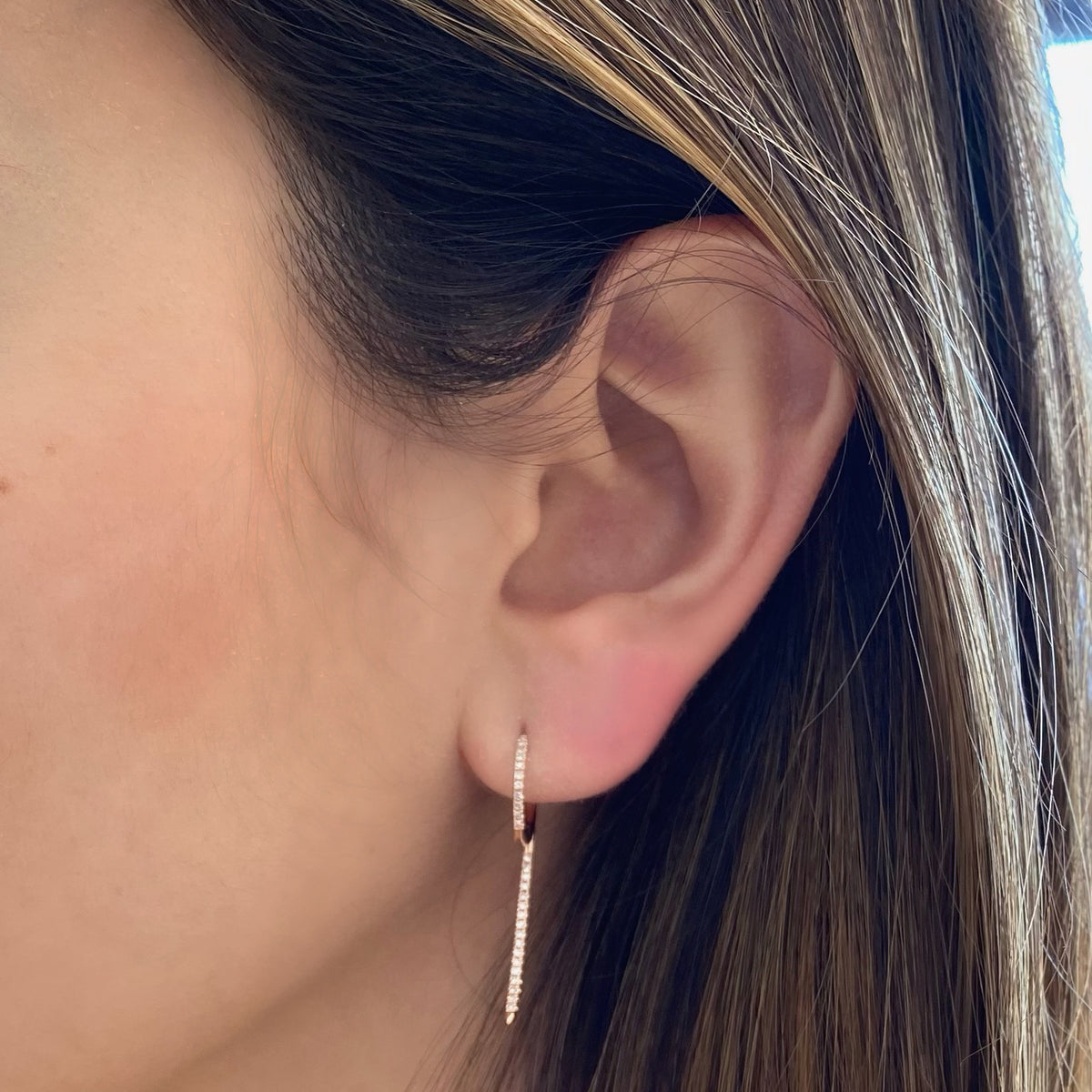 Female model wearing Diamond '9' huggie earrings - 14K gold  - 0.18 cts round diamonds