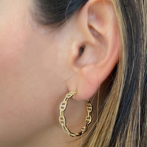 Female model wearing Diamond Oval Link Hoop Earrings - 14K yellow gold weighing 8.80 grams  - 188 round diamonds weighing 0.60 carats