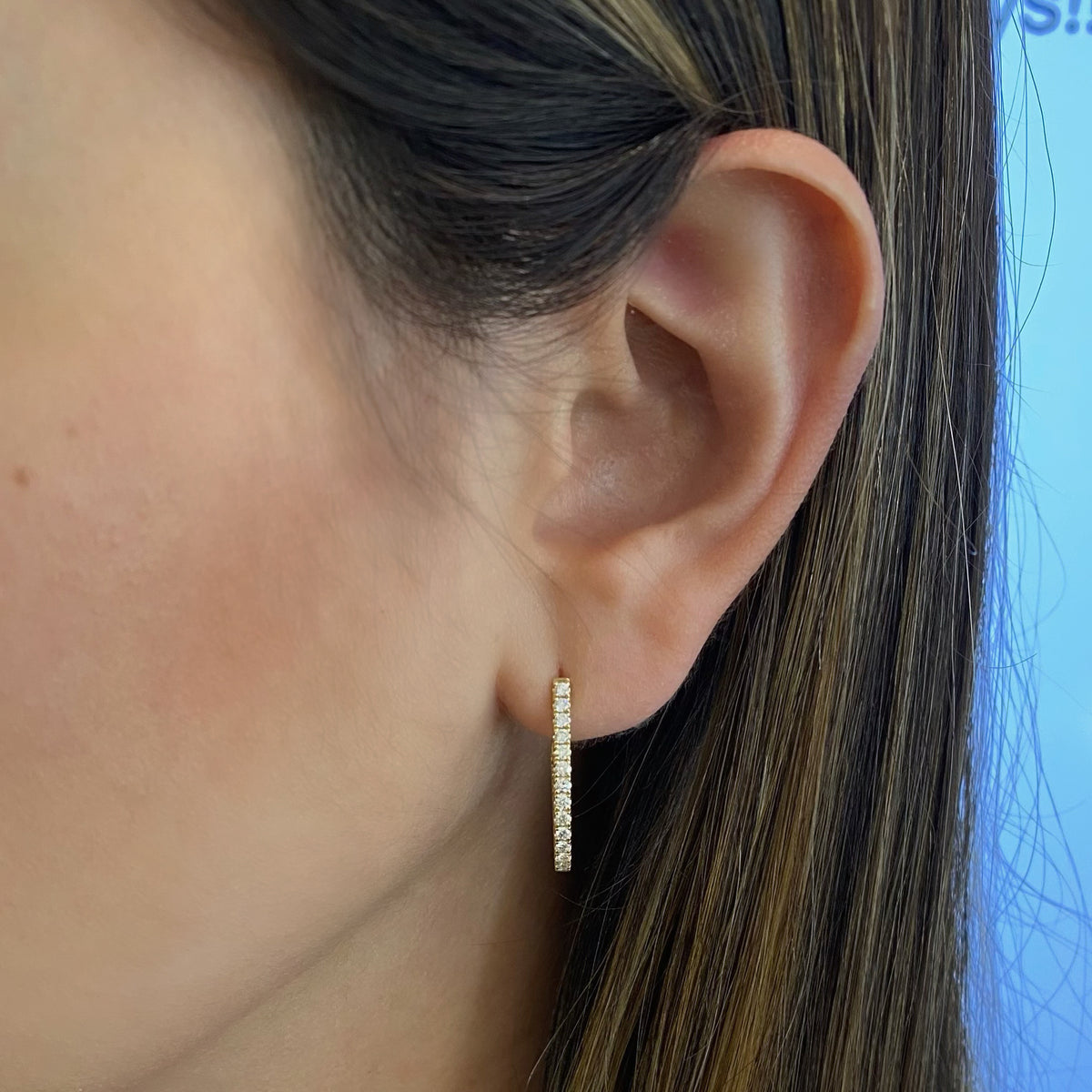 Female model wearing Inside-out diamond oval huggie earrings -18k gold weighing 3.91 grams -44 round diamonds weighing .67 carats