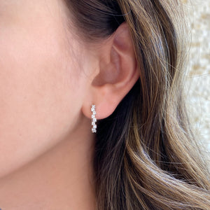 Female model wearing Diamond zig-zag huggie earrings - 18K gold weighing 3.79 grams  - 18 round diamonds totaling 0.56 carats