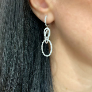 Female Model Wearing Diamond Oval Dangle Earrings  The ideal accessory for your next cocktail party or special occasion.  -18K gold weighing 7.23 grams  -186 round diamonds totaling 1.73 carats